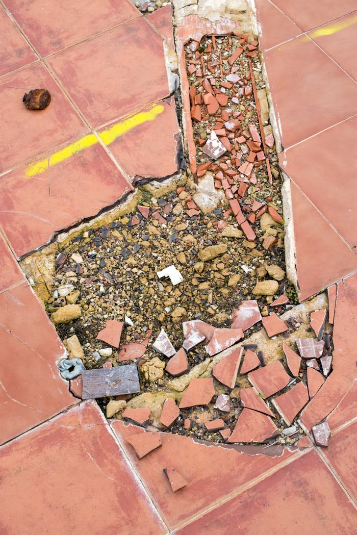 Cracked tile floor revealing underlying debris and broken materials.